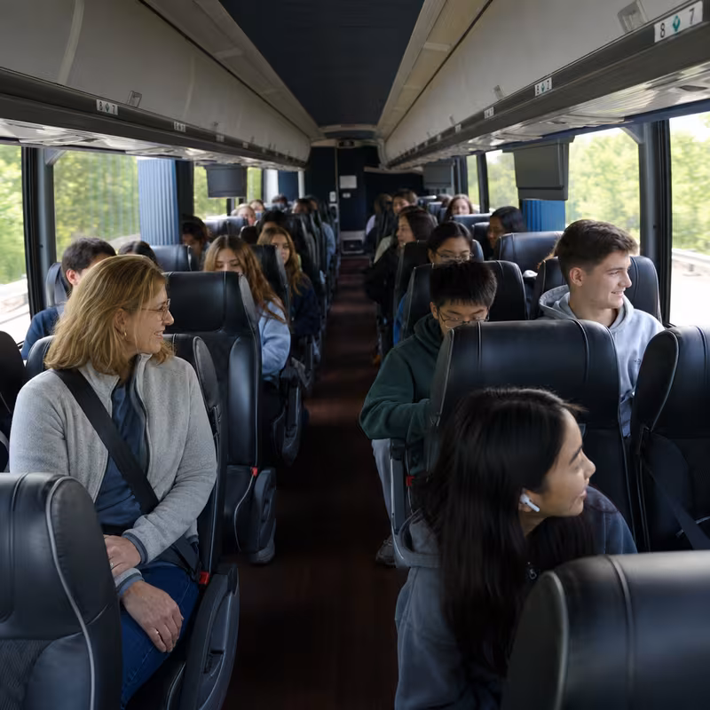Group boarding a white charter bus for School Transportation transportation in New Orleans